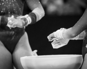 general purpose black and white image of gymnasts adjusting grips and chalking up