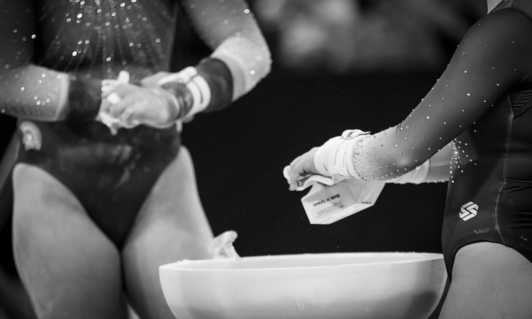 general purpose black and white image of gymnasts adjusting grips and chalking up