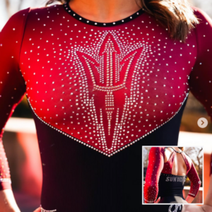 Red and black long-sleeved gymnastics leotard. The upper red section features a prominent, stylized trident emblem formed by numerous white rhinestones. The red fabric transitions into a black lower section. The neckline is black with silver rhinestones. An inset image shows the back of the leotard with a keyhole cutout and a horizontal "Sun Devils" across the back.