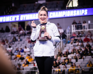 Norah Flatley makes a "money" gesture while accepting an NCAA trophy.
