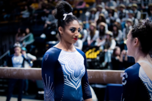 California's Kyana George standing next to the beam talking to a teammate before her routine