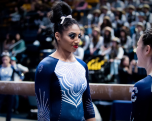 California's Kyana George standing next to the beam talking to a teammate before her routine