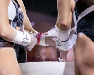 gymnasts around a chalk bucket with just their torsos and grips and hands in the frame