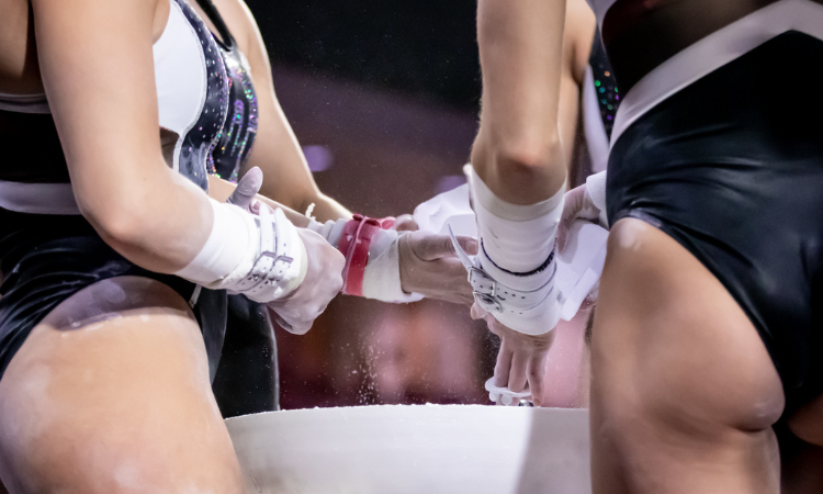 gymnasts around a chalk bucket with just their torsos and grips and hands in the frame