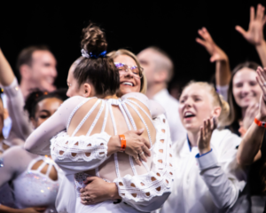 Leah Clapper hugs Jenny Rowland while teammates cheer in the background