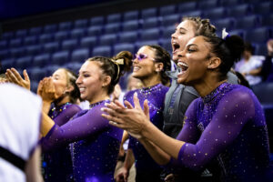 Washington gymnasts cheer and clap for a teammate