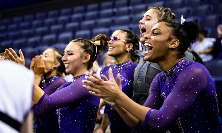 Washington gymnasts cheer and clap for a teammate