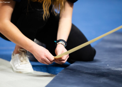 A manager lays tape on the floor exercise