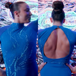 A gymnast wears a vibrant blue University of Florida leotard. The front features a high neckline with a sleek, seamless design accented by intricate, cascading rhinestone patterns that create a sense of dynamic movement. The back of the leotard has a dramatic, open cutout framed by a unique, crisscross wrap design at the lower back. A small clasp secures the high neckline at the back. The bright blue color reflects the school's signature shade.