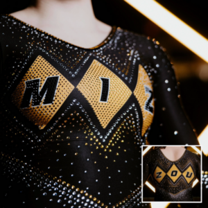 Close-up of Missouri gymnastics' new black leotard featuring bold gold diamond shapes across the chest that spell "MIZ" in black letters outlined in white. The leotard is covered in silver and gold rhinestones in a chevron pattern. An inset image in the bottom right corner shows a gymnast posing in the leotard, with a low scoop back and more rhinestone detailing.