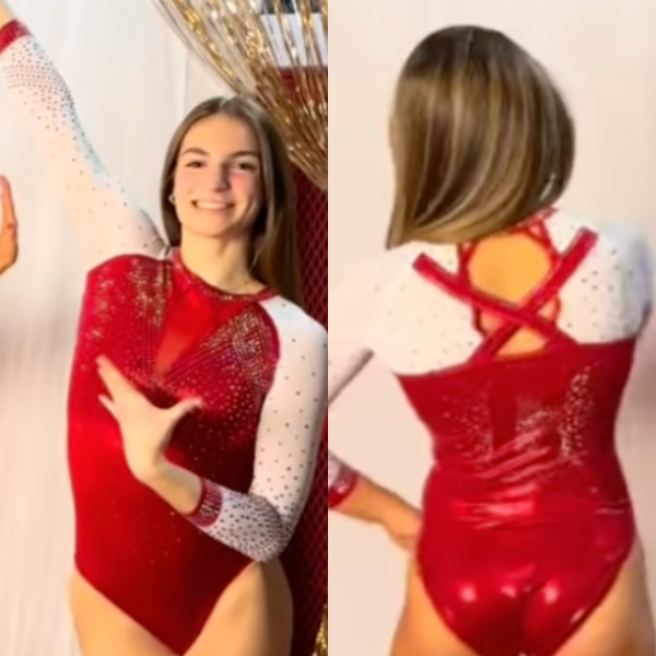 A gymnast wearing a red and white long-sleeved leotard. The front design features a deep red body with sheer sleeves and rhinestone accents running along the arms and chest. The back showcases an elegant strappy design with a bold red criss-cross pattern against the white backdrop.