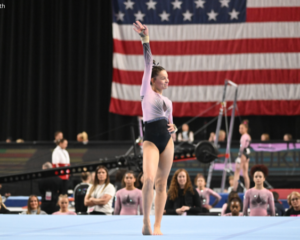 Haley Mustari stands with one arm raised on floor.