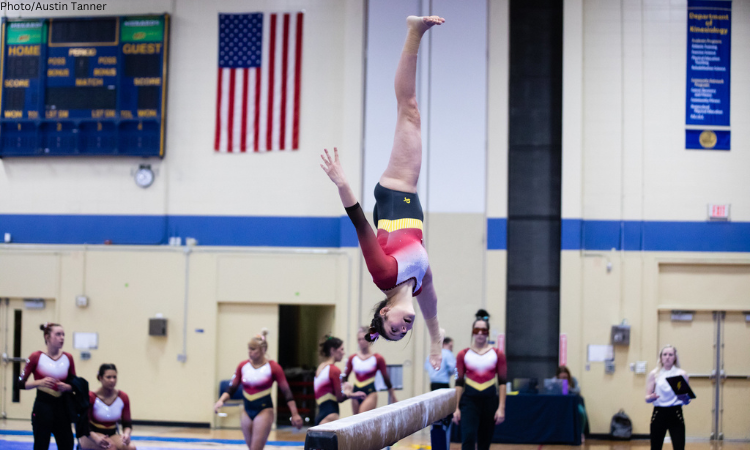 Isabelle Brown is upside down, mid-flip on beam.