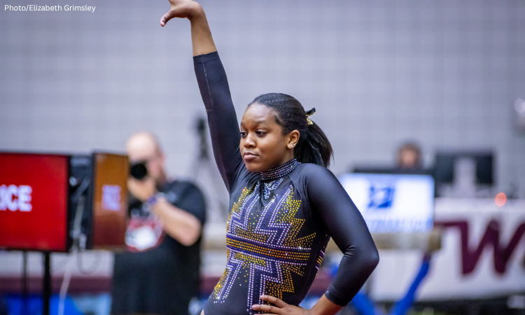 Morgan Price poses on floor with one hand on her hip and the other raised.