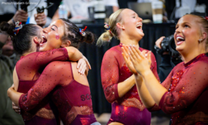 Oklahoma gymnasts clap, hug each other, and celebrate the team's victory.