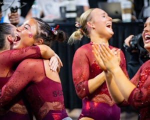 Oklahoma gymnasts clap, hug each other, and celebrate the team's victory.