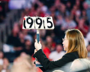 A woman holds up a 9.95 score card at a gymnastics meet.
