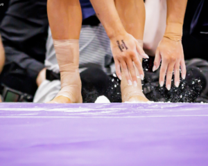 A closeup of a gymnast's hands and feet as they reach toward the floor