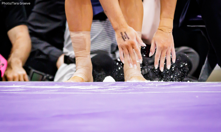 A closeup of a gymnast's hands and feet as they reach toward the floor