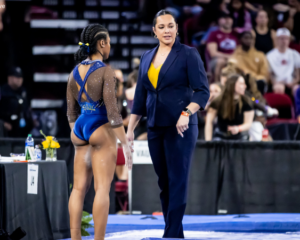 Maile’ana Kanewa-Hermelyn speaks to Sierra Brooks on the slidelines of a gymnastics meet.