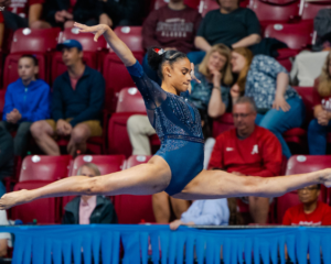 Ondine Achampong wearing a blue leotard does a split leap on floor