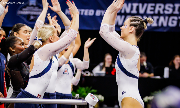 Arizona gymnasts, including Alysen Fears, celebrate after a routine, raising their arms for high-fives while wearing white and navy leotards.