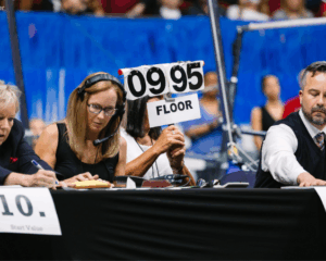 College women's gymnastics judges hold up a sign showing a 9.95 score given to an athlete