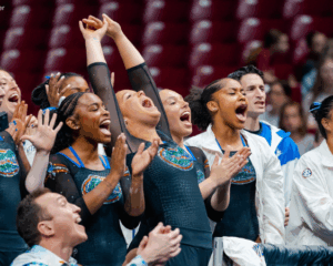 The Florida gymnastics team, including Ly Bui, Selena Harris-Miranda, and Skye Blakely, cheer from the sidelines.