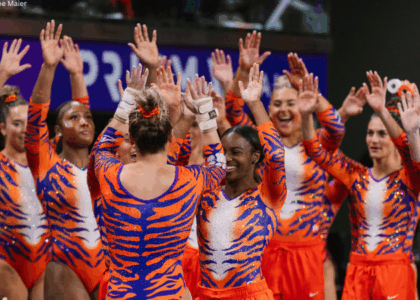 Clemson gymnasts in tiger stripe leotards offer their teammate high fives