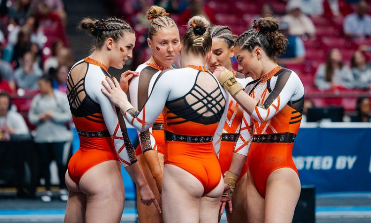 Oregon state gymnasts in a huddle on the floor
