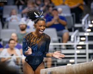 Florida gymnast Selena Harris-Miranda jumps and claps in celebration after finishing her beam routine.