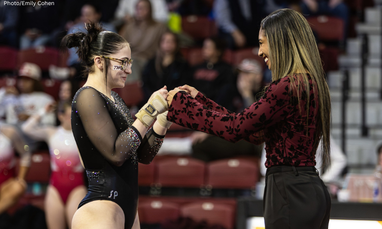 Kyana George gives a smile and a fist bump to a TWU gymnast
