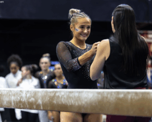 Sophia Isbell from Texas Woman's gets a fist bump from her coach before her beam routine.