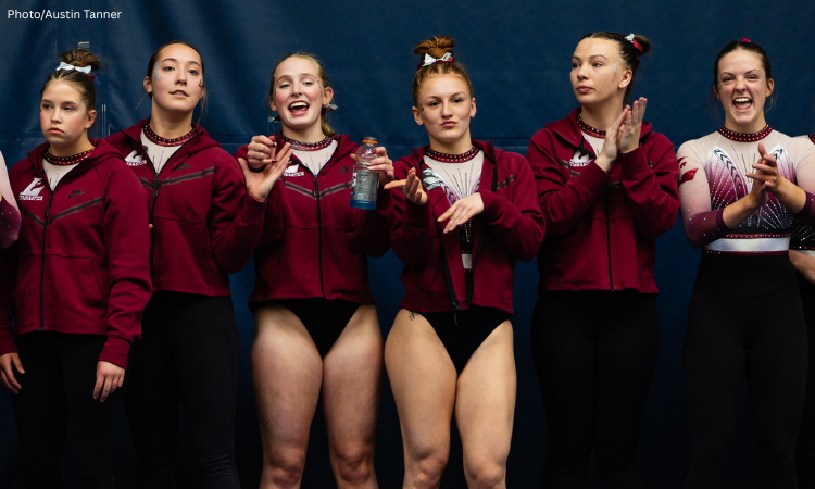 A team of gymnasts stands on the sidelines. Each gymnast has a unique facial expression