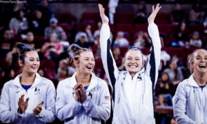Air Force student athletes smile at a women's gymnastics meet against Denver in March 2024