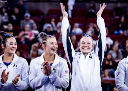 Air Force student athletes smile at a women's gymnastics meet against Denver in March 2024