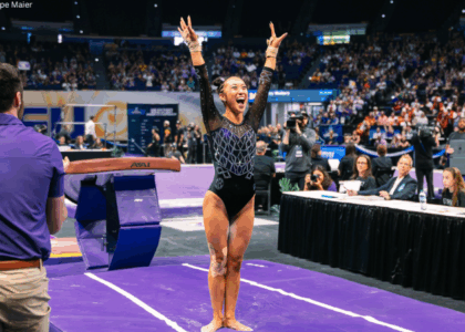 Kailin Chio lands a stuck vault and smiles with both arms up.