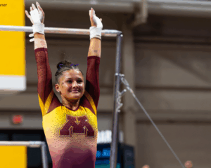 Jordyn Lyden dismounts bars with a big smile.