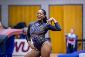 Morgan Price poses on floor and smiles with one hand on her hip and one on her shoulder.