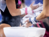 Two gymnasts stand by a chalk bucket chalking their grips.
