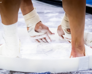 Close-up shot of gymnast chalking up in chalk bucket.