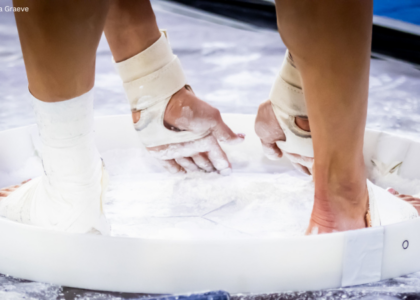 Close-up shot of gymnast chalking up in chalk bucket.