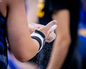 Gymnast chalks their grips for bars.