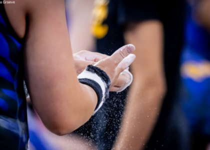 Gymnast chalks their grips for bars.