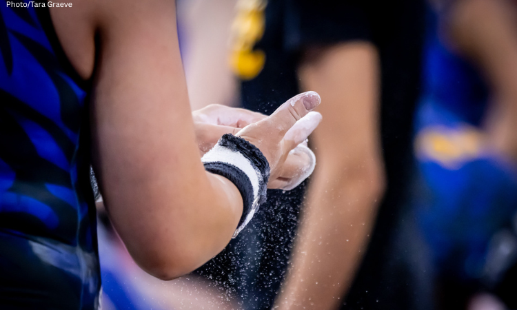 Gymnast chalks their grips for bars.