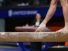 Gymnast stands on the beam with one foot pointed in front of them.