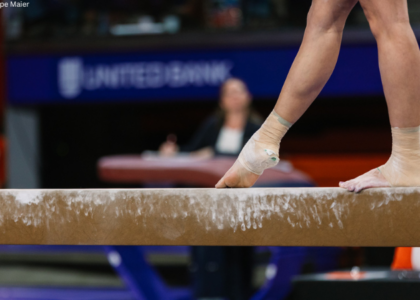 Gymnast stands on the beam with one foot pointed in front of them.