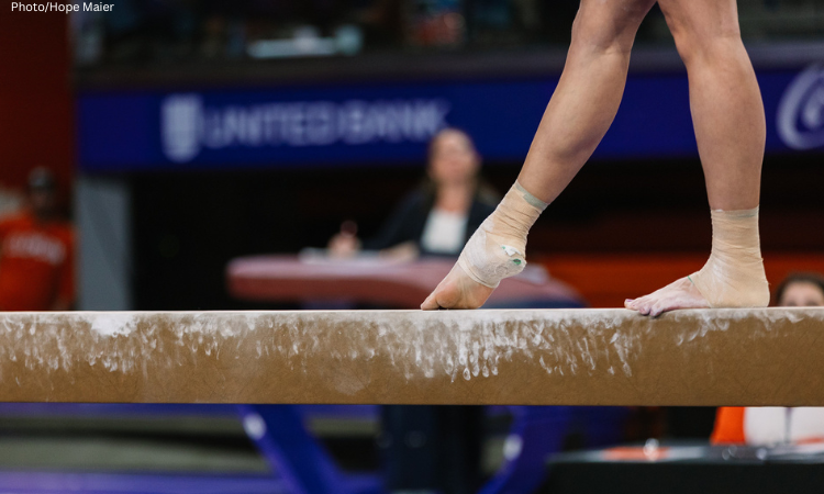 Gymnast stands on the beam with one foot pointed in front of them.