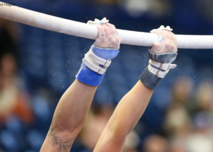 Close-up of gymnast swinging on bars.