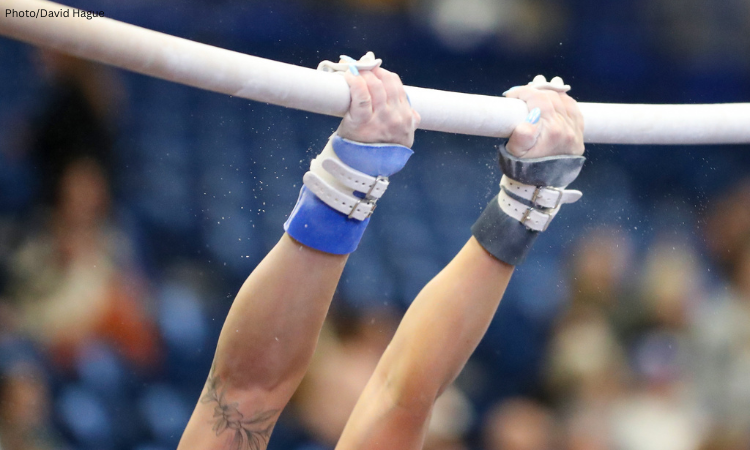 Close-up of gymnast swinging on bars.